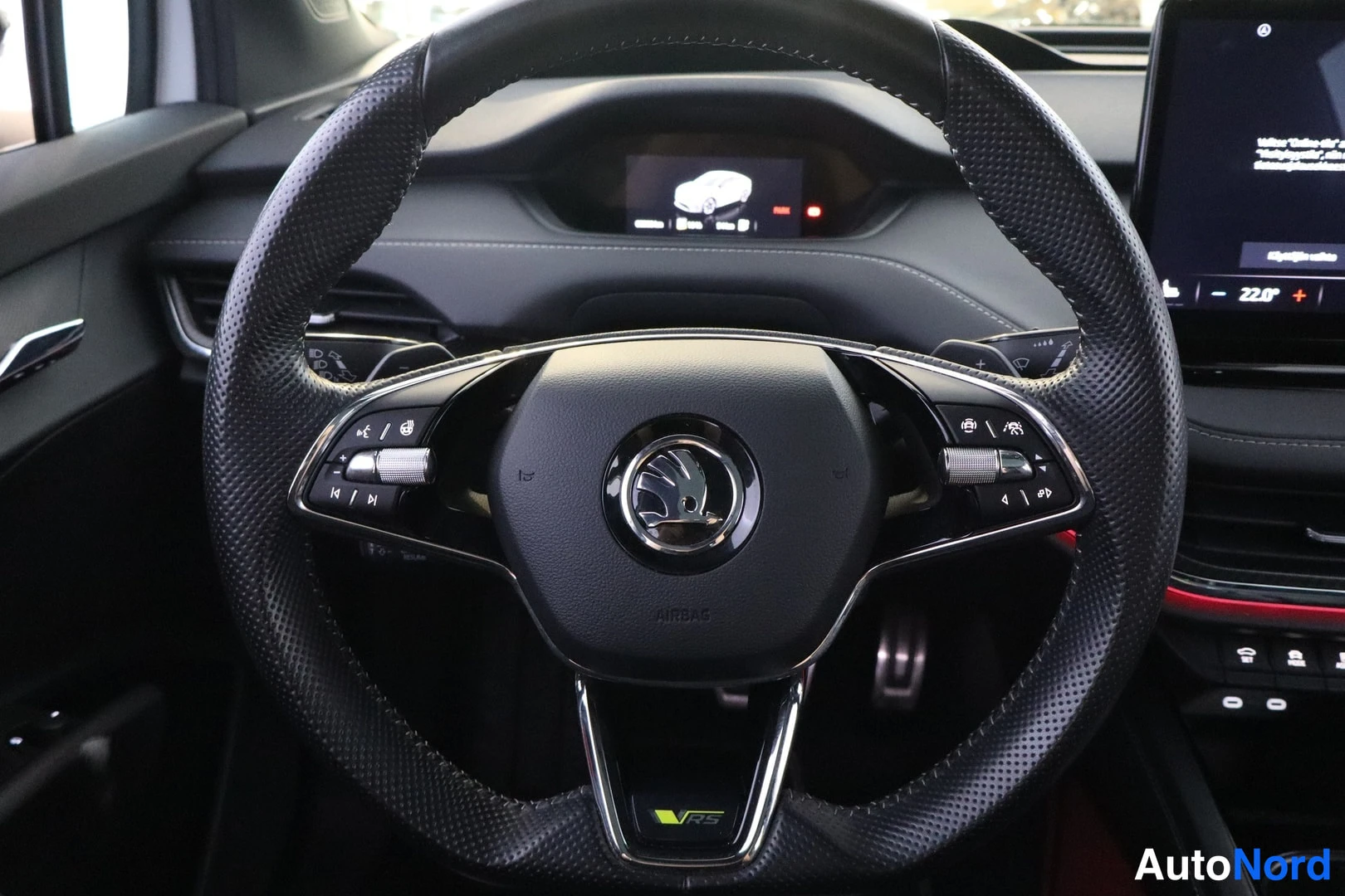 Sivulta: Skodan ohjauspyörä vRS-merkinnällä ja AIRBAG-tekstillä, kojelauta ja osa infotainment-näytöstä taustalla.