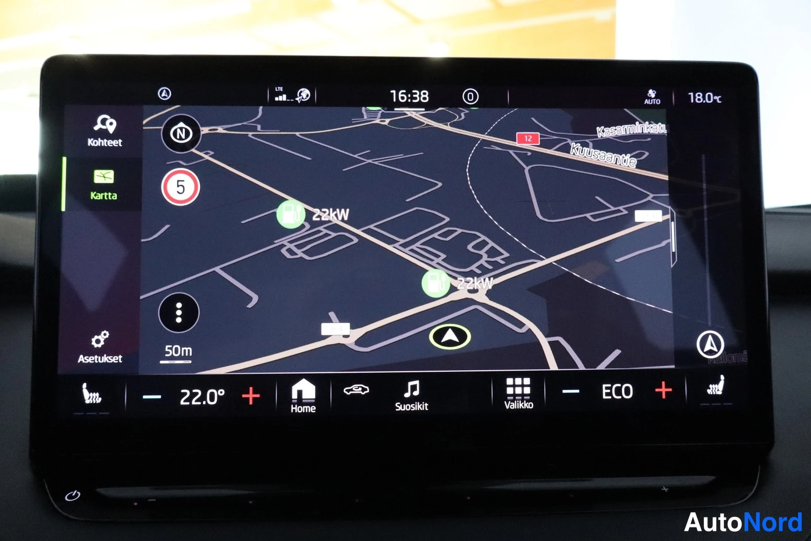 Muu: Infotainment-näytön karttanäkymä reitillä: kaksi 22 kW latauspistettä kartalla, kadunnimet Kasarminkatu ja Kuusaaantie, vasemmalla Kohteet-, Kartta- ja Asetukse
