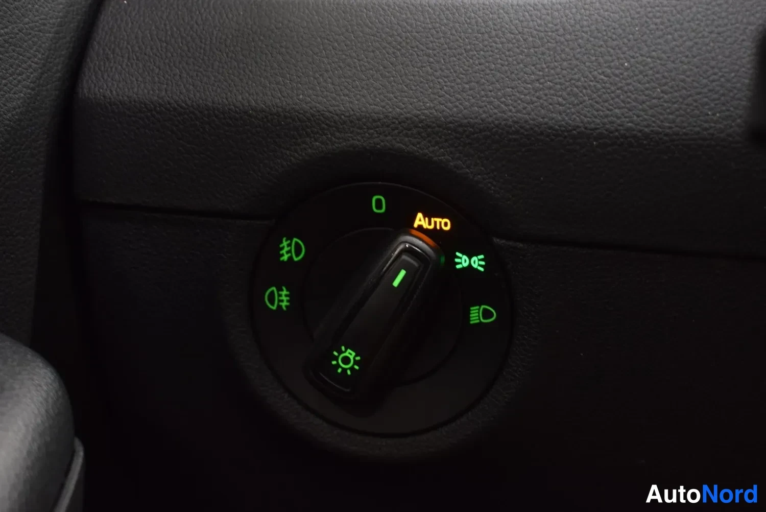 Sivulta: Ajovalokytkin lähikuvassa, AUTO-merkinta valaistuna oranssilla; kytkimessä myös sumuvalot ja valaistuksen merkkivalot.