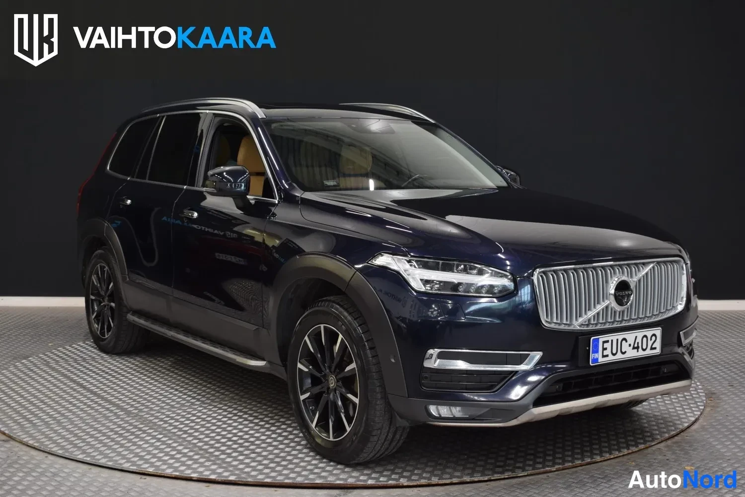 Etuviisto, nokka oikealle: Tummansininen Volvo XC90 etuviistöstä oikealta, etusäleikkö ja -rekisterikilpi näkyvissä.