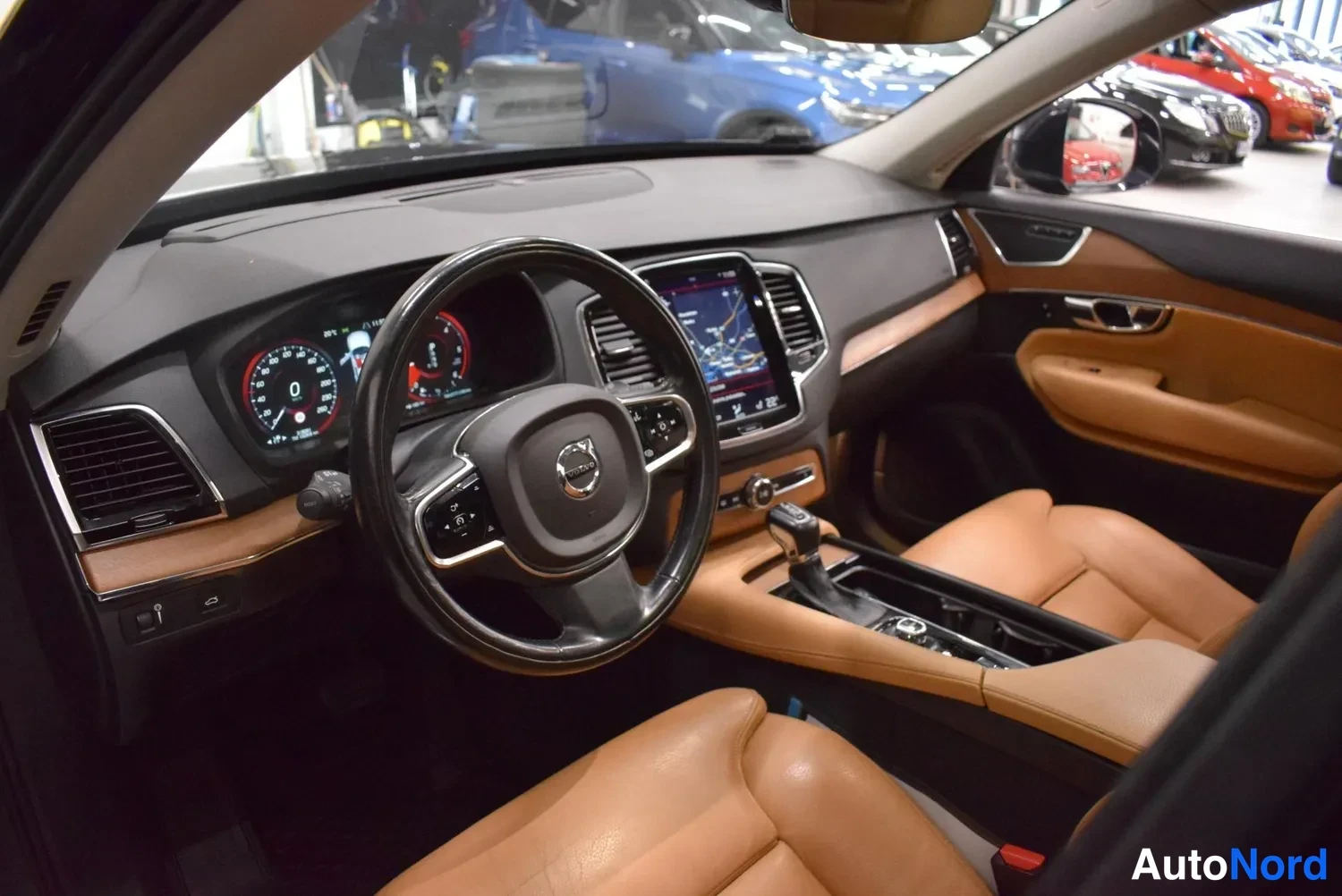 Muu: Volvo XC90:n ohjaamo vasemmalta: ohjauspyörä, mittarit, keskikonsolin näyttö ja ruskeat nahkaistuimet.
