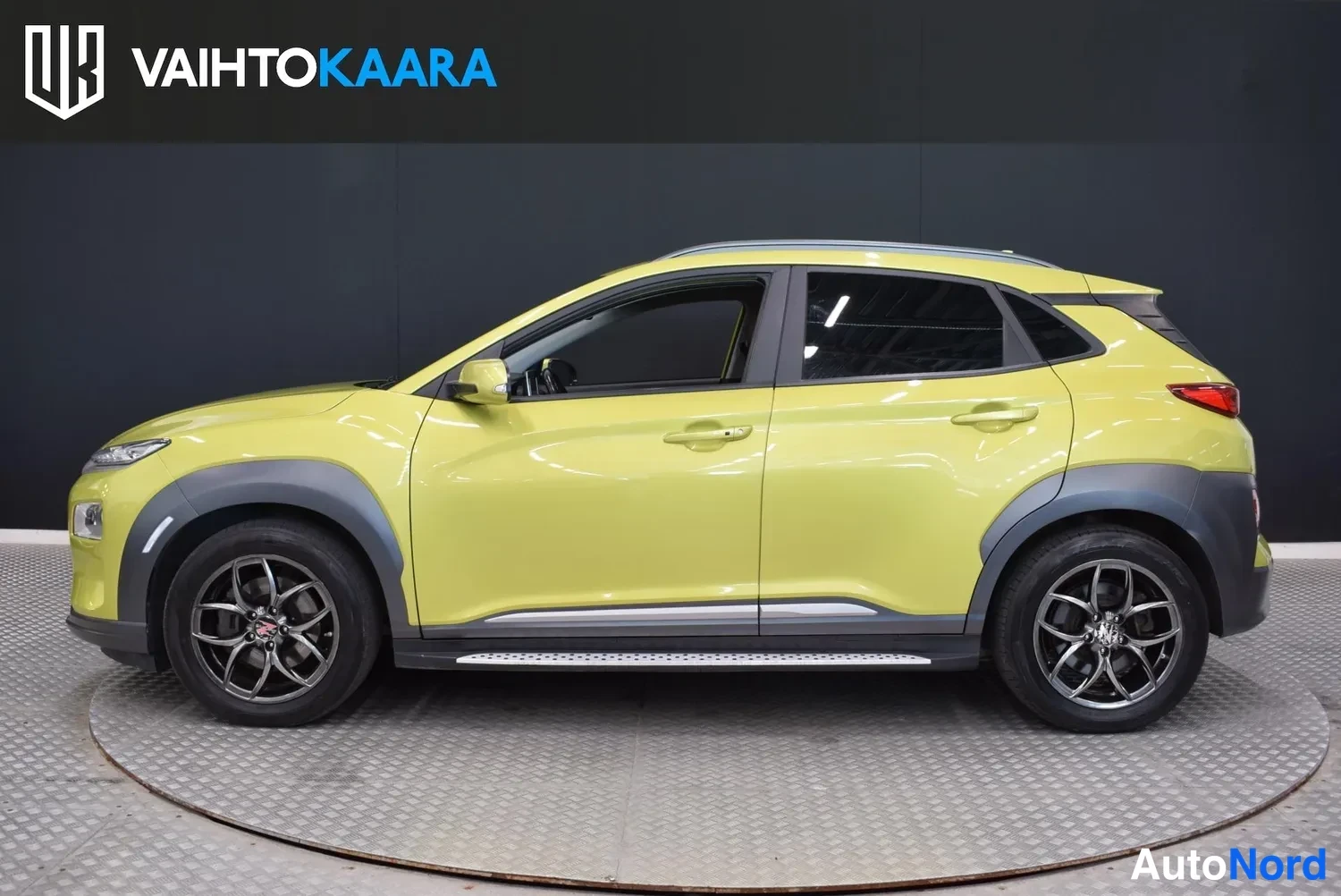 Sivulta: Keltavihreä Hyundai Kona sivusta vasemmalta, sisätiloissa alustalla.