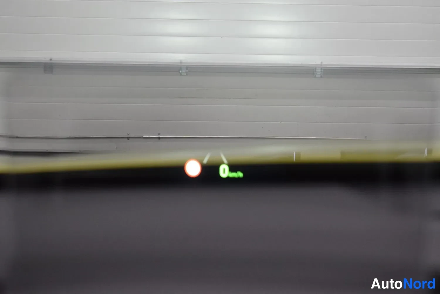 Yksityiskohta: Instrumentpanelens speedometer visar 0 km/h och en varningslampa lyser, bilden är suddig.