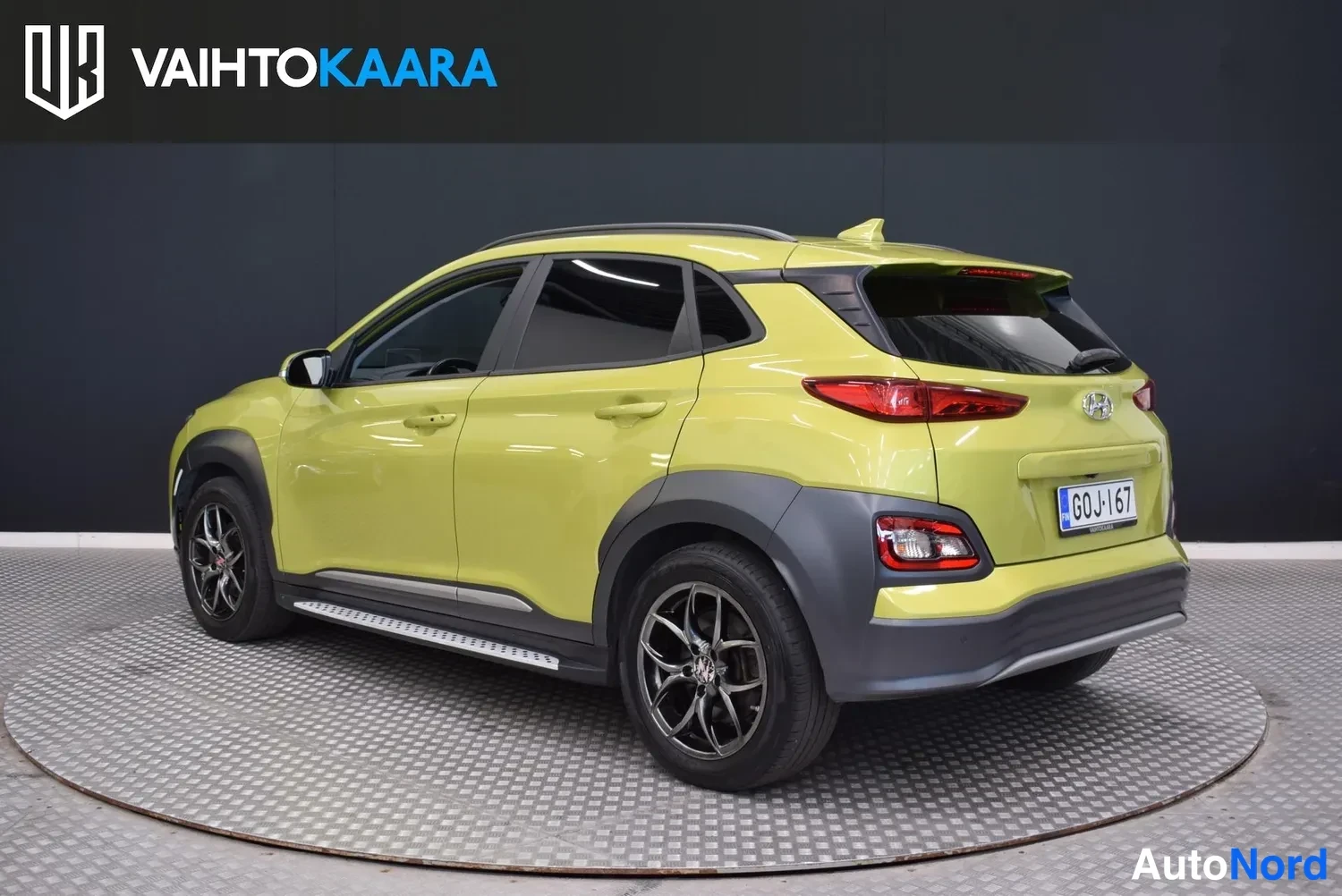 Takaviisto: Keltavihreä Hyundai Kona takanurkasta vasemmalta, takavalot ja rekisterikilpi näkyvissä.
