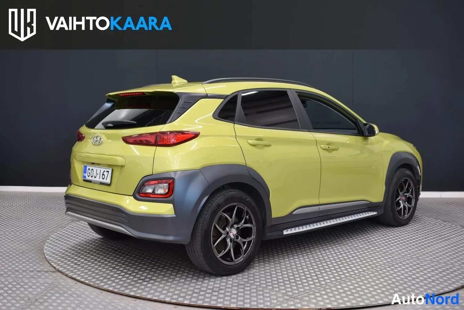 Takaviisto: Keltavihreä Hyundai Kona takanurkasta oikealta, rekisterikilpi G0J-167 näkyvissä.