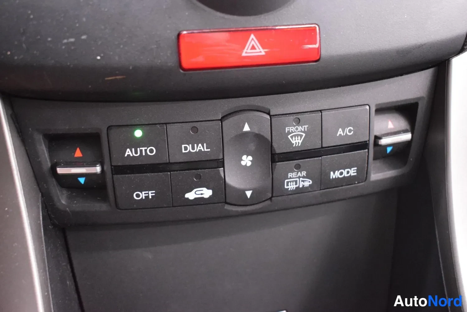 Muu: Lähikuva ilmastointipaneelista AUTO-, DUAL-, A/C- ja MODE-painikkeilla sekä punaisella varoituskolmiopainikkeella