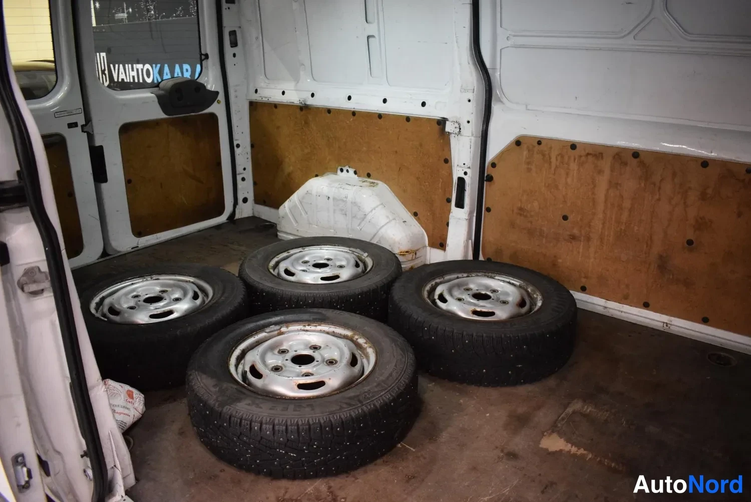 Muu: Pakettiauton lastitila, jossa vierii neljä talvirengasta vanhalla kevytmetallivanteella.