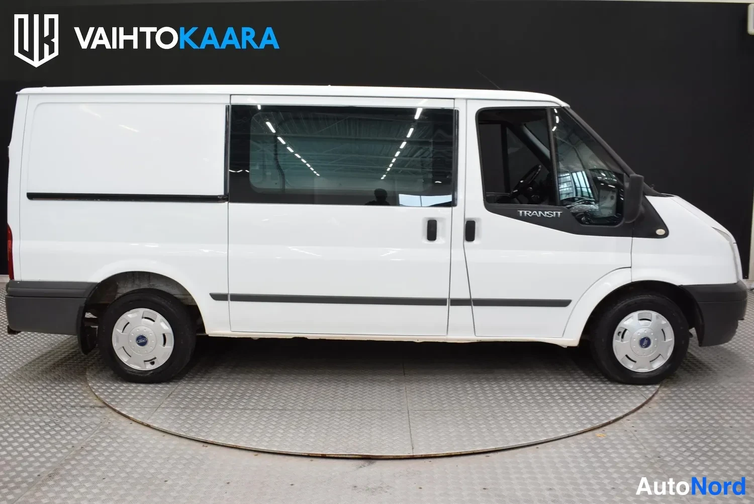 Sivulta: Ford Transit -pakettiauto sivulta, valkoinen koripaneeli ja mustat puskurit.