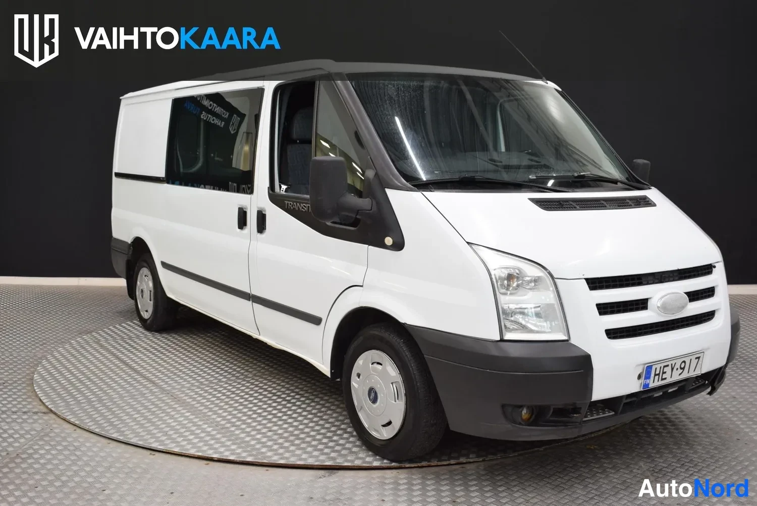 Etuviisto, nokka oikealle: Ford Transit -pakettiauto etuviistöstä, keula oikealla, valkoinen koripaneeli.