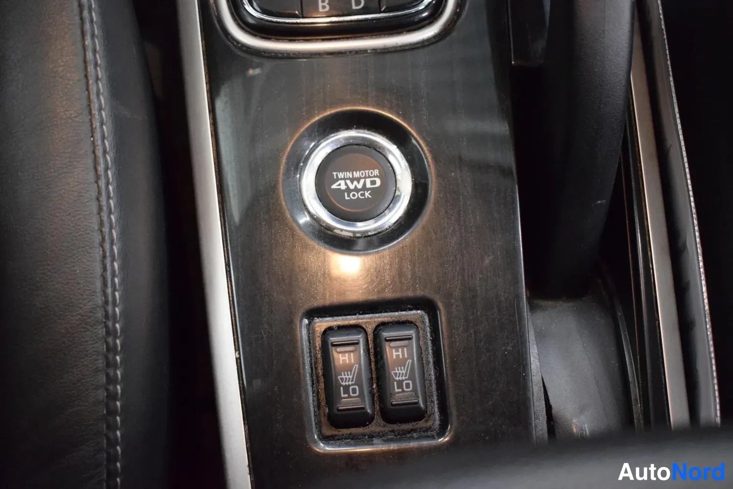Yksityiskohta: Keskiössä TWIN MOTOR 4WD LOCK -painike ja alla kaksi lämmitettävien istuinten kytkinpainiketta (HI/LO).