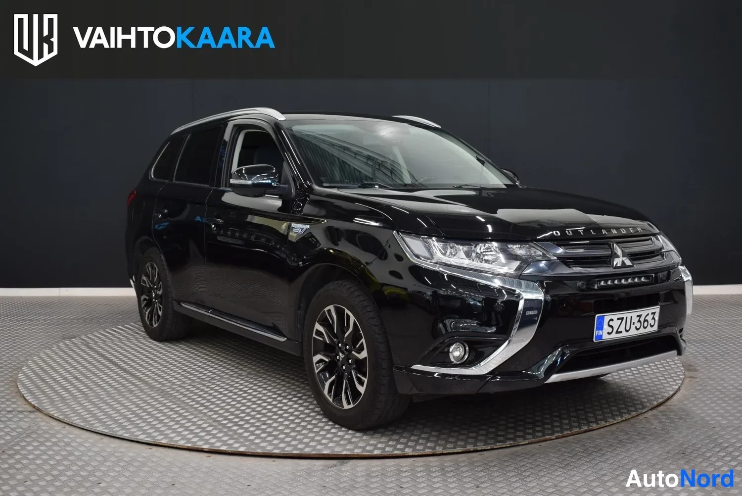 Etuviisto, nokka oikealle: Mustan Mitsubishi Outlanderin etukulma oikealta, ET-levyinen rekisteri, PHEV-merkintä etulokasuojassa.