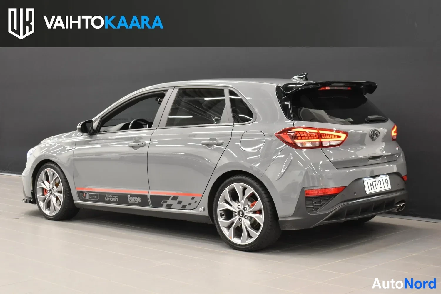 Takaviisto: Hyundai i30 -viistopyykkö harmaana takanäkymä hieman sivulta, musta spoileri ja punaiset takavalot näkyvät.