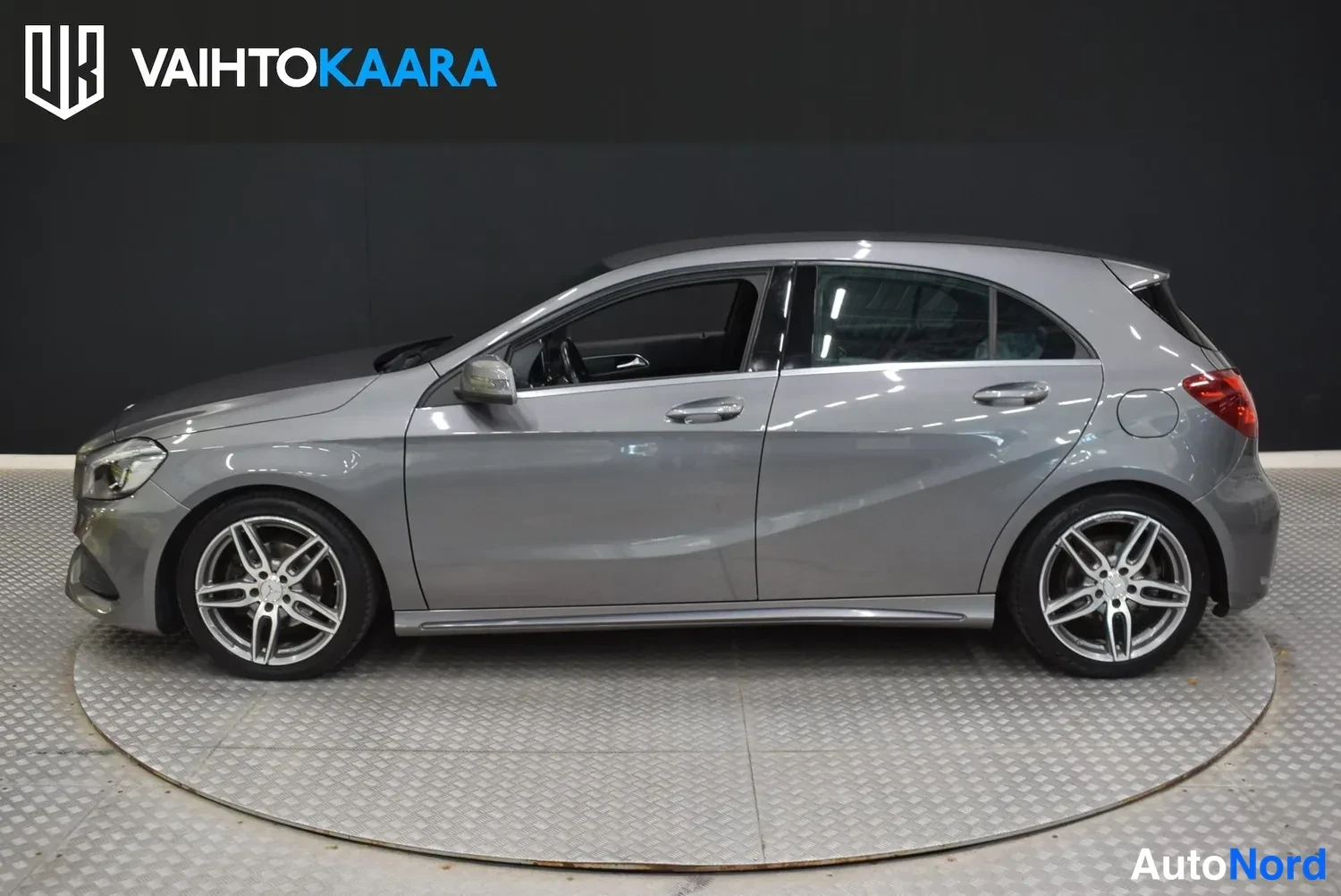 Sivulta: Harmaan Mercedes-Benz A-mallin sivuprofiili oikealta puolella studioalbumissa, AMG-tyyliset viisisakaraiset vanteet näkyvät.