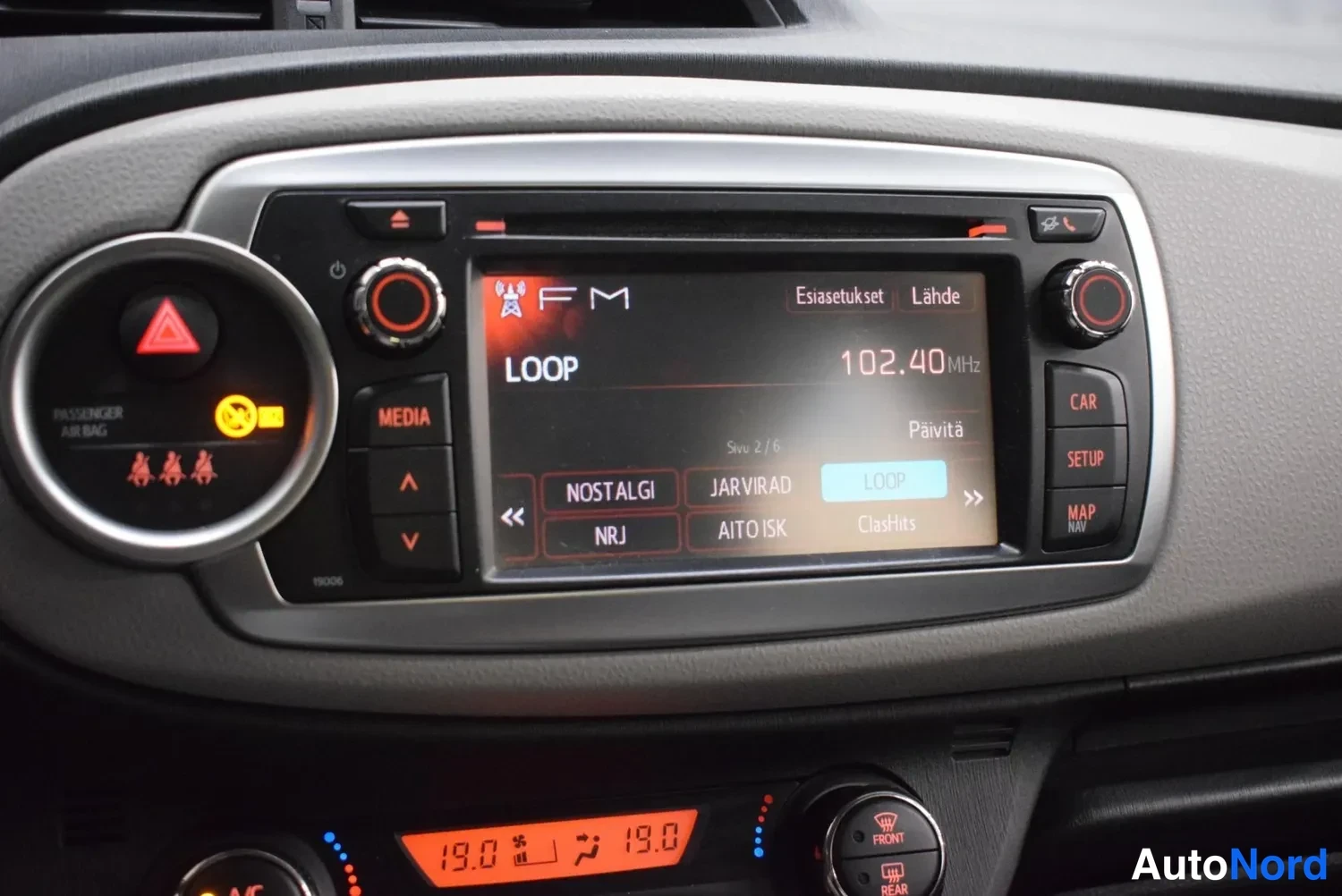 Muu: Kojelauta: medianäyttö näyttää FM-radiota taajuudella 102.40 MHz, kanava LOOP, säädönapeit MEDIA ja CAR/SETUP/MAP, ilmastointipaneeli näyttää 19.0 astetta.