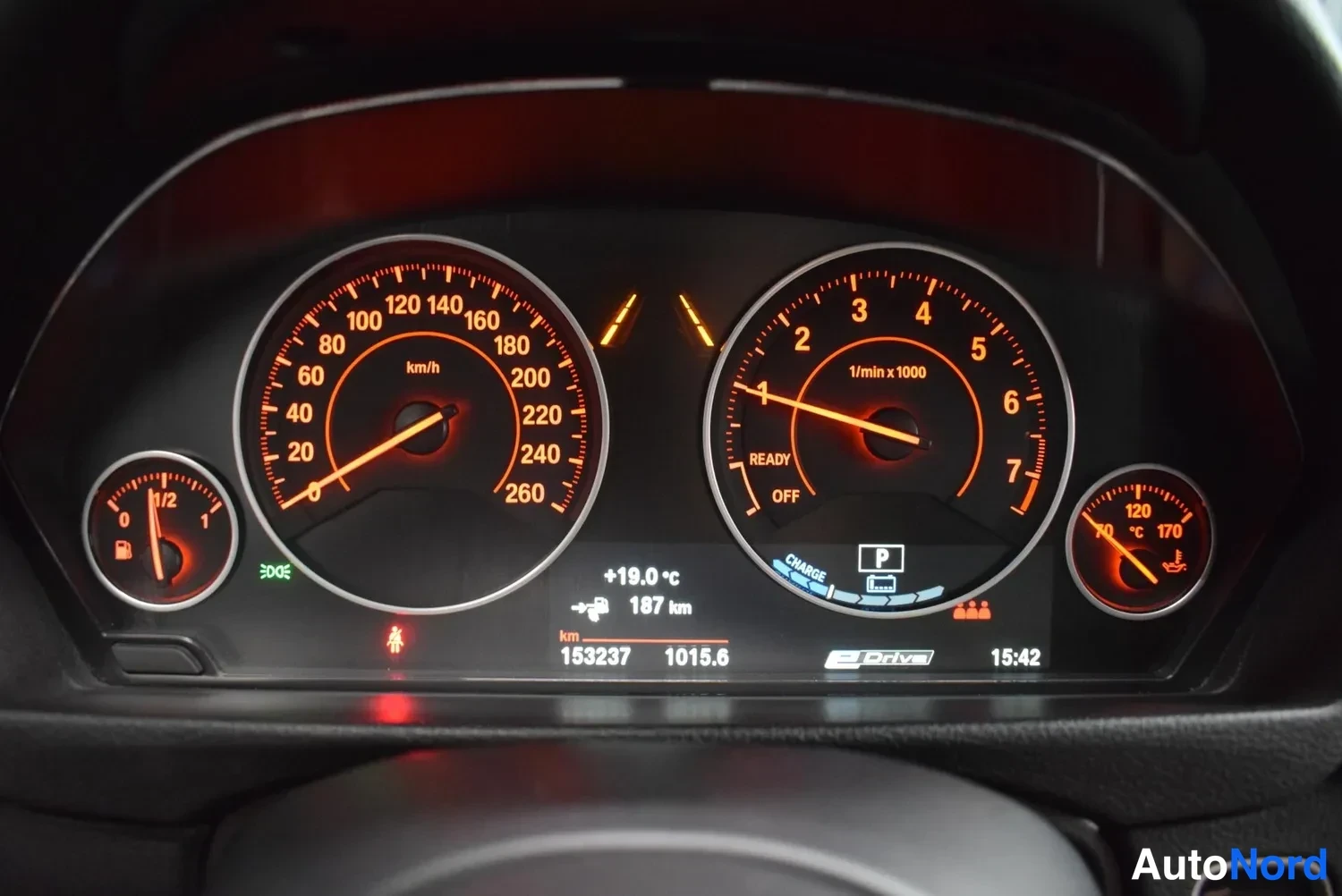 Muu: BMW:n mittaristo: nopeusmittari ja kierrosmittari oranssilla valaistuksella, matkamittari 153237 km, ajotietokone näyttää 187 km ja +19,0 °C, Edrive-merkintä nä