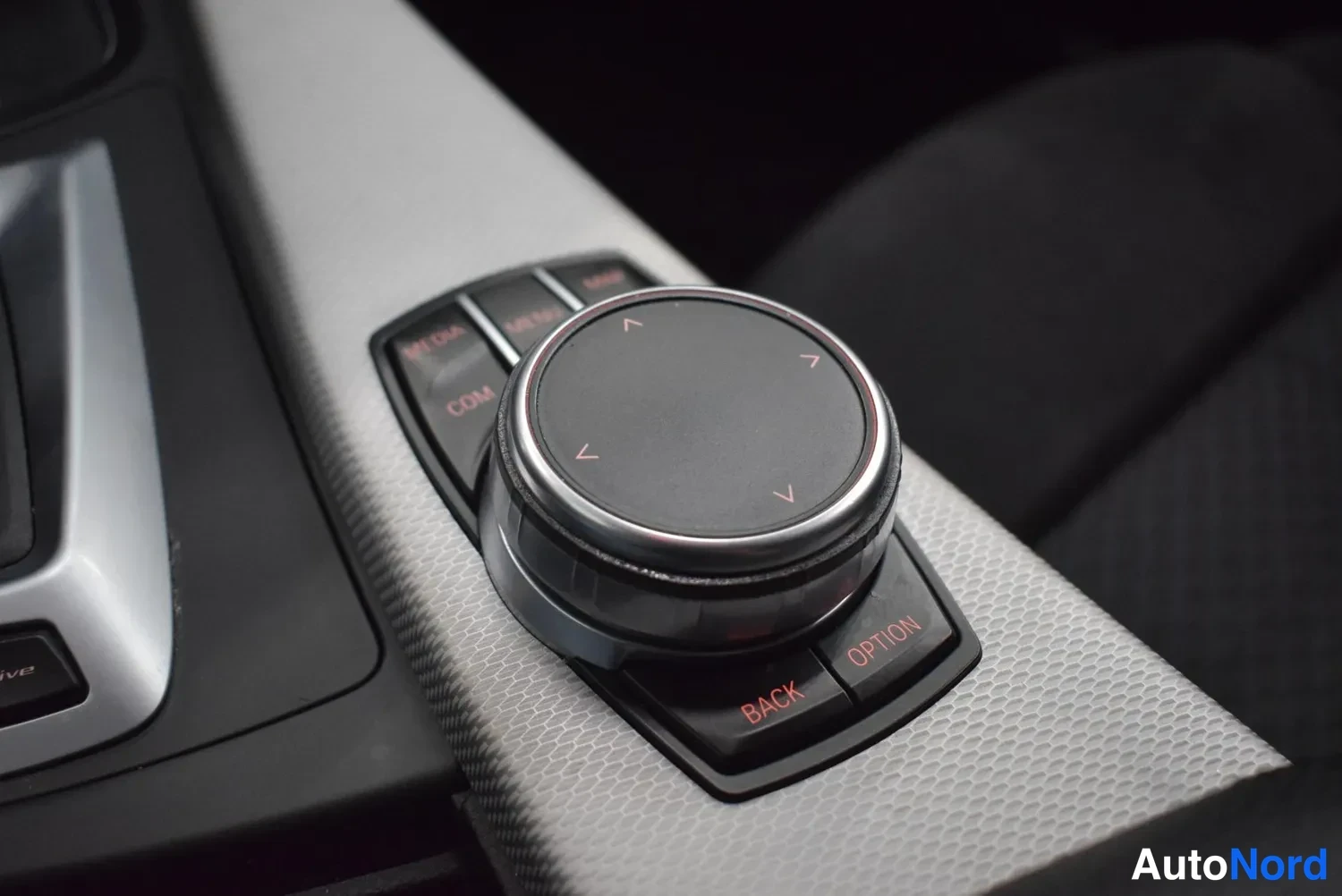 Muu: Keskikonsolin iDrive-ohjainsäädin ympyränapeilla BACK ja OPTION.