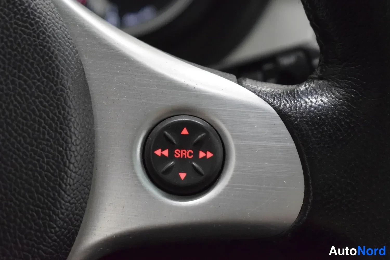 Yksityiskohta: Ohjauspyörän nuolinäppäimistö, jonka keskellä lukee SRC, ohjaa auton infotainment-järjestelmää.
