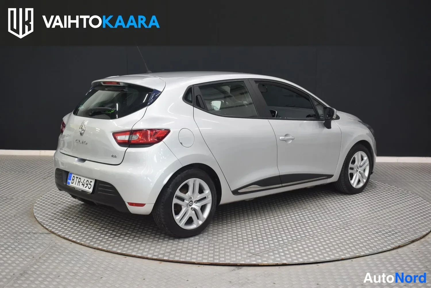 Takaviisto: Hopeanvärinen Renault Clio viistosti takaa, perä vasemmalla, rekisterillä.