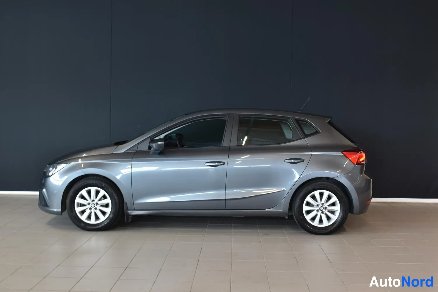 Sivulta: Seat Ibizan sivuprofiili kuvattuna vasemmalta, viistoperäinen harmaa viisiovinen hatchback.
