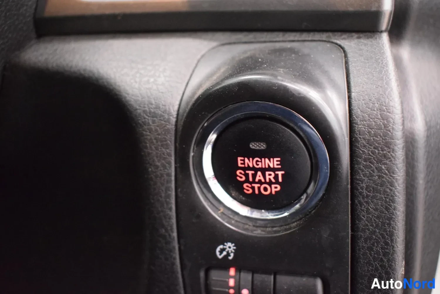 Muu: Avaimeeton käynnistyspainike lähikuvassa, teksti ENGINE START STOP punaisella valaistuna.