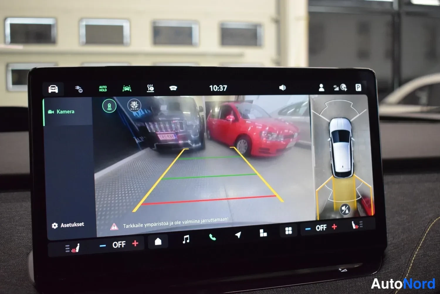 Muu: Keskinäytöllä näkyvä peruutuskameran kuva autotallista, parkkipäivistreilit ja lintuperspektiivin apunäkymä.
