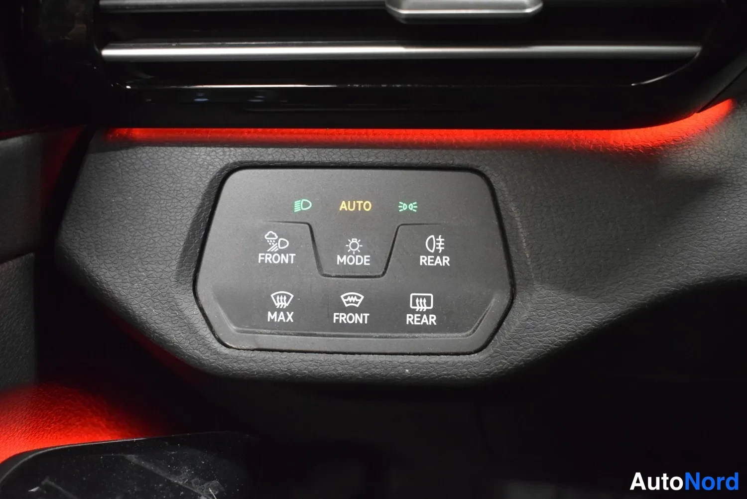 Muu: Läheiskuva auton valojen hallintapainikkeista: AUTO, FRONT, MODE, REAR, MAX, FRONT ja REAR, taustalla punainen valaistus.