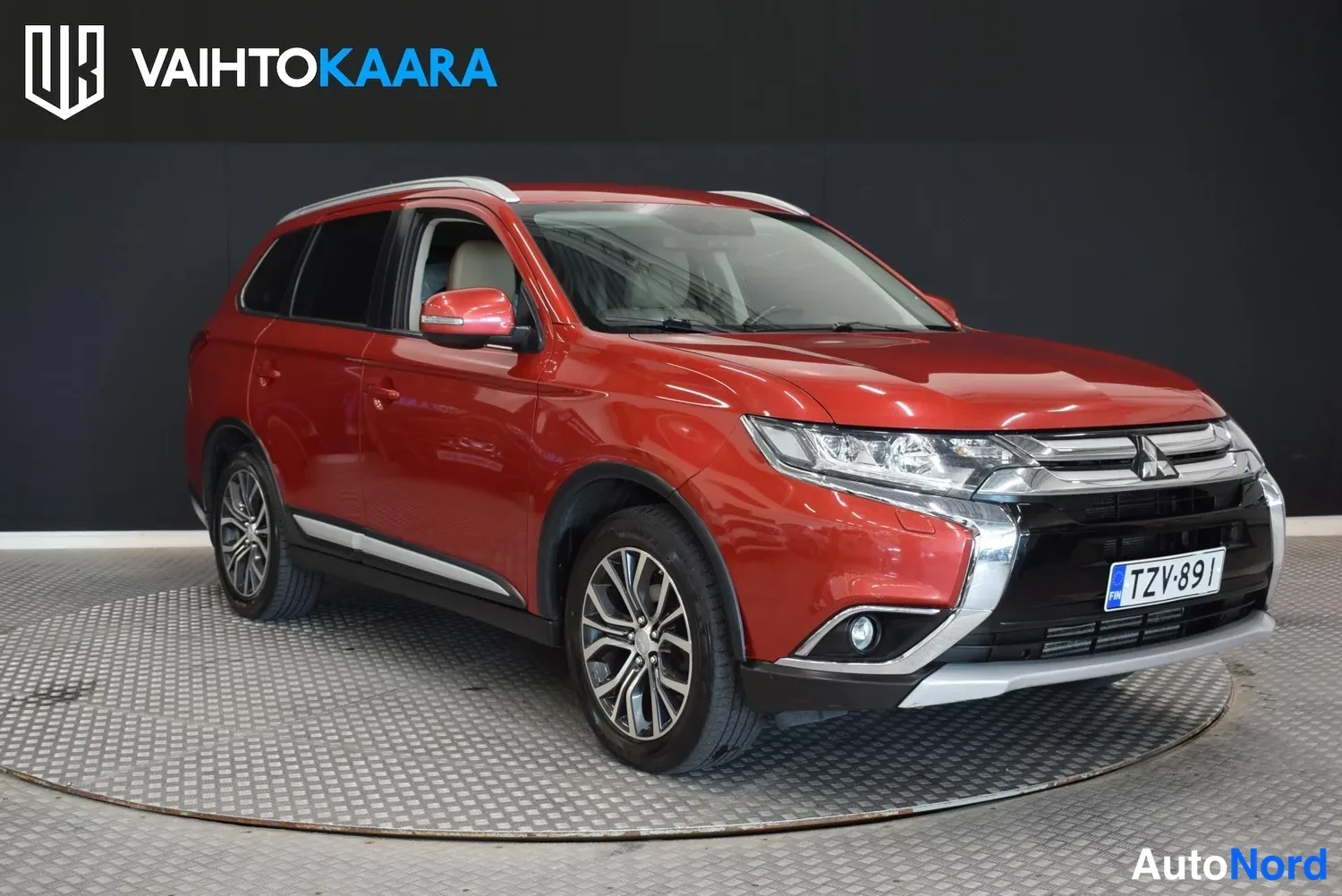 Etuviisto, nokka oikealle: Punaisen Mitsubishi Outlanderin etu kolmanneskulma oikealta; keulak grille ja etummaisen helma näkyvät, rekisteri.