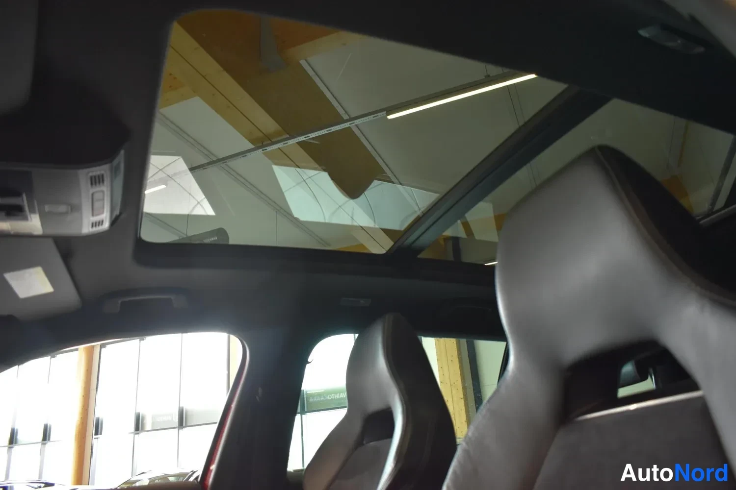 Yksityiskohta: Panoraamikatto sisältä katsottuna, tummat urheiluistuimet ja auton takaosaan avautuva lasikatto.