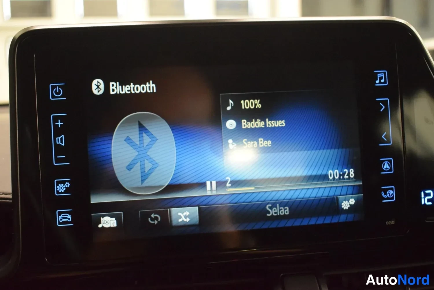 Muu: Auton infotainment-näyttö näyttää Bluetooth-musiikkitoiston: kappale 'Baddie Issues', esittäjä Sara Bee, toiston kesto 00:28.