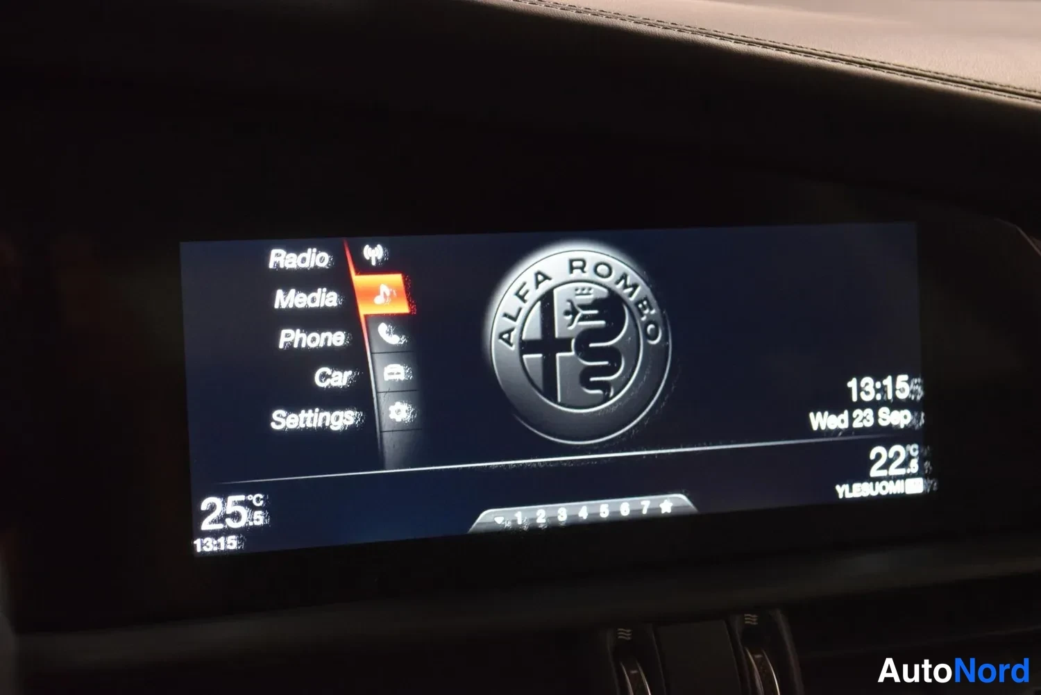 Muu: Radio- ja multimediasysteemin valikko Radio, Media, Phone, Car ja Settings, näytöllä Alfa Romeon logo, kello 13:15, pvm Wed 23 Sep, lämpötilat 25 ja 22 astetta.