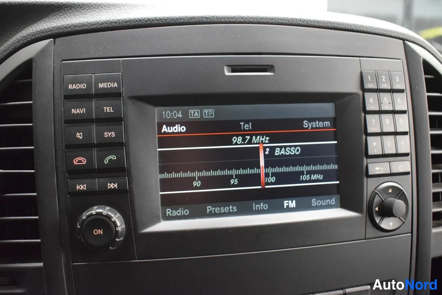 Muu: Keskikonsolin infotainment-laite näyttää FM-radiota taajuudella 98,7 MHz, näppäimistö RADIO, MEDIA, NAVI ja TEL näkyvät.