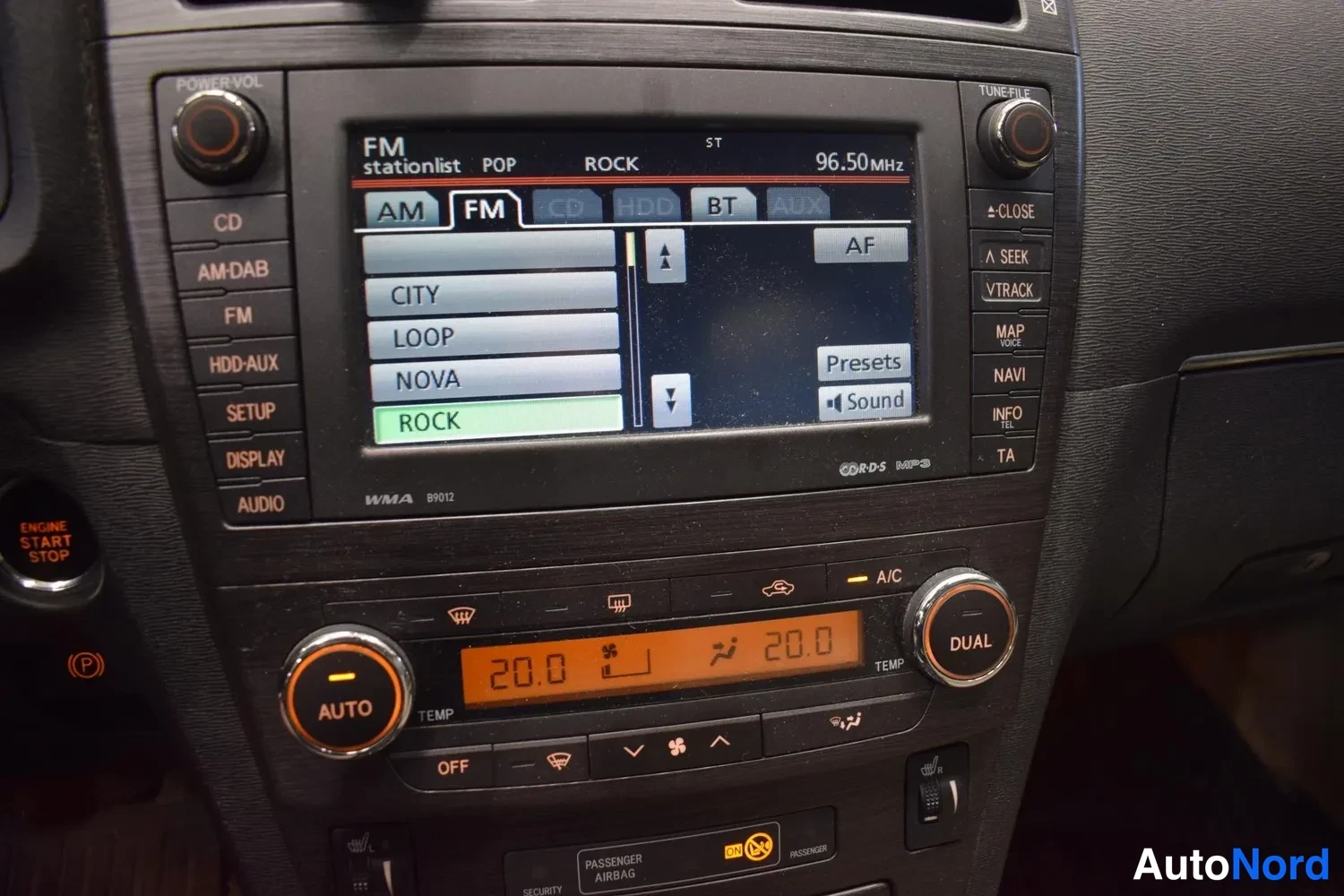 Muu: Kojelaudan keskusyksikön näyttö ja painikkeet; radiossa FM ROCK 96,50 MHz ja kaksivyöhykeilmastointi asetettuna 20,0 asteeseen.