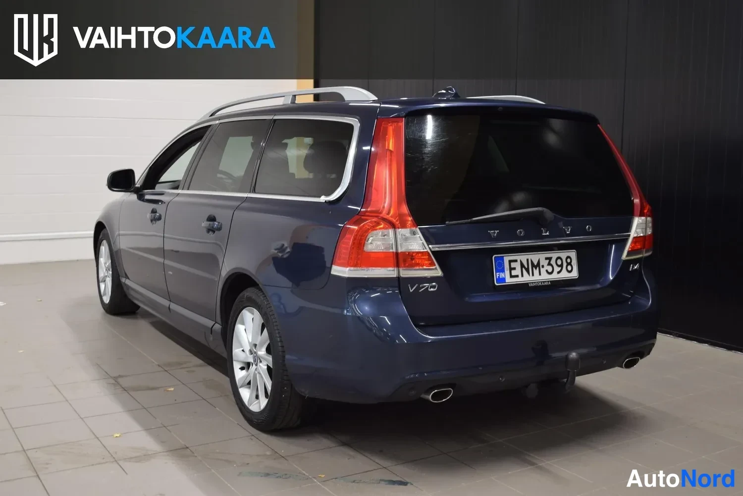 Takaviisto: Sininen farmariauto takanurkasta sisätiloissa, takavalot, pakoputket ja perävaunukoukun kiinnitys näkyvät.