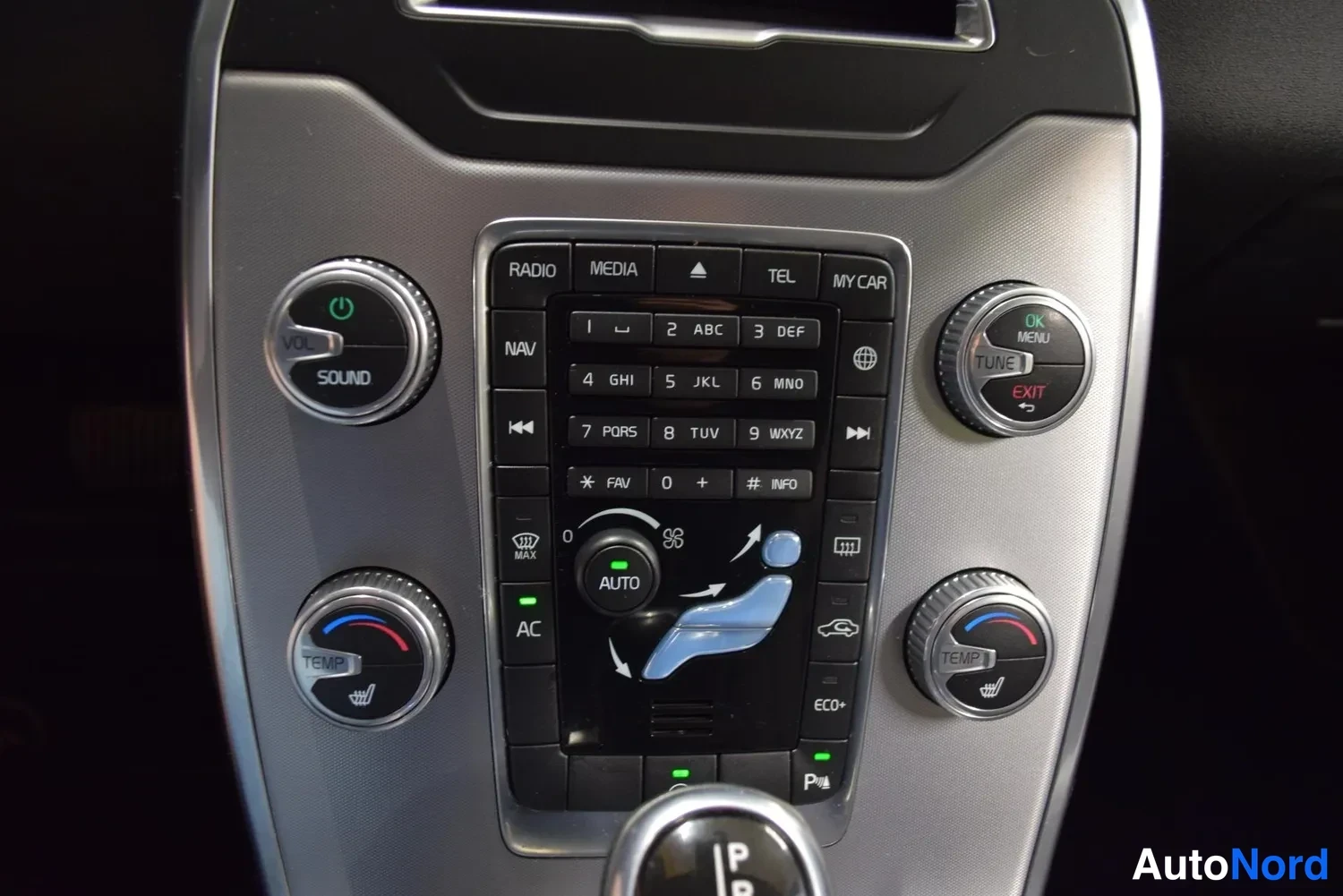 Muu: Takaisinpeili- ja kojelautanäkymä auton keskikonsolinhallinta: radio, media, NAV, TEMP- ja AUTO-napit.