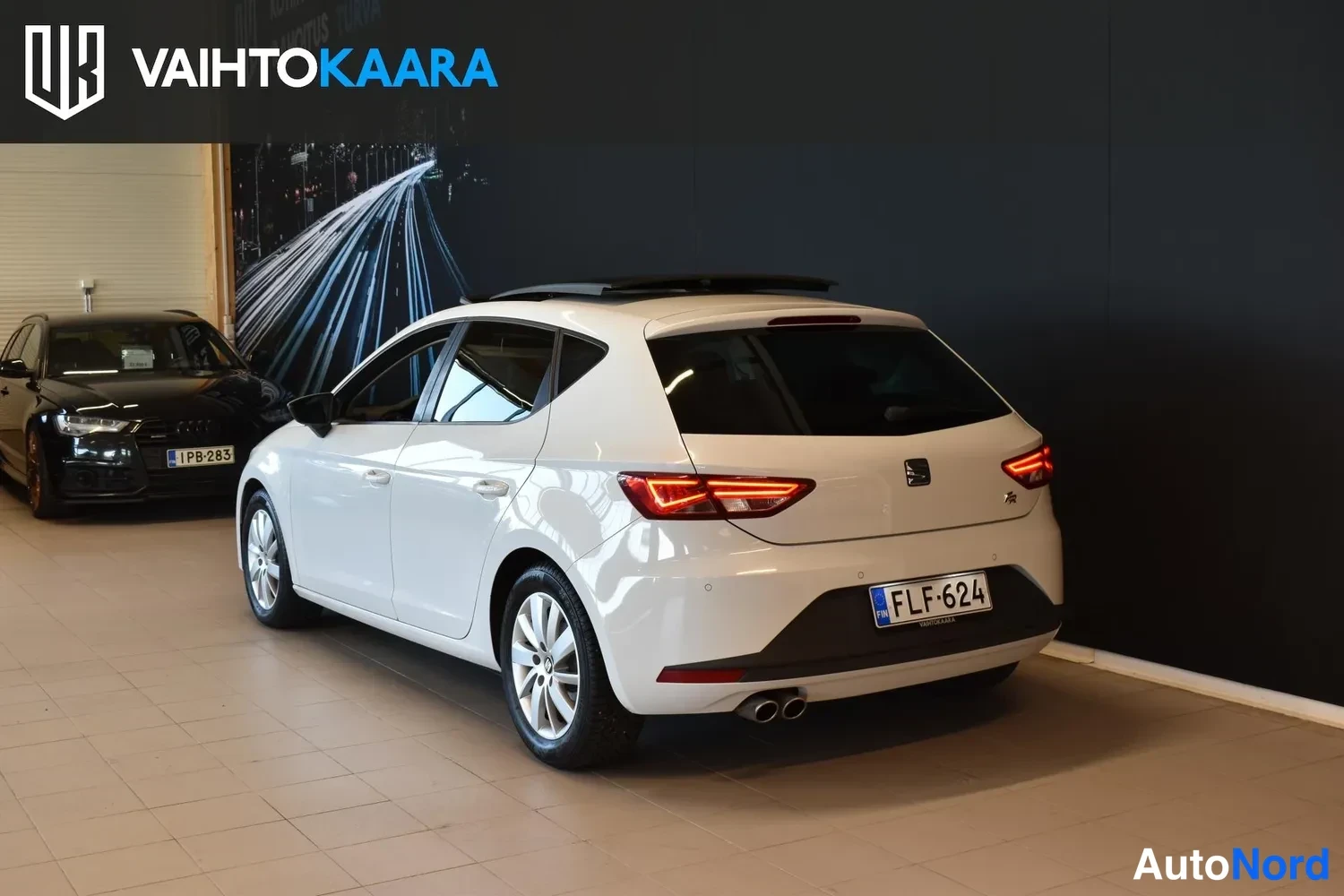 Takaviisto: Valkoinen Seat Leon takaa oikealta viistosti, rekisteritunnus, kaksoispakoputki näkyvissä.
