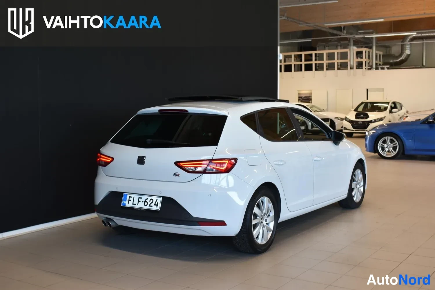 Takaviisto: Auton takaosa viistosti oikealta: valkoinen Seat Leon, punaiset takavalot, rekisterikilpi, FR-merkintä ja kattoluukku.