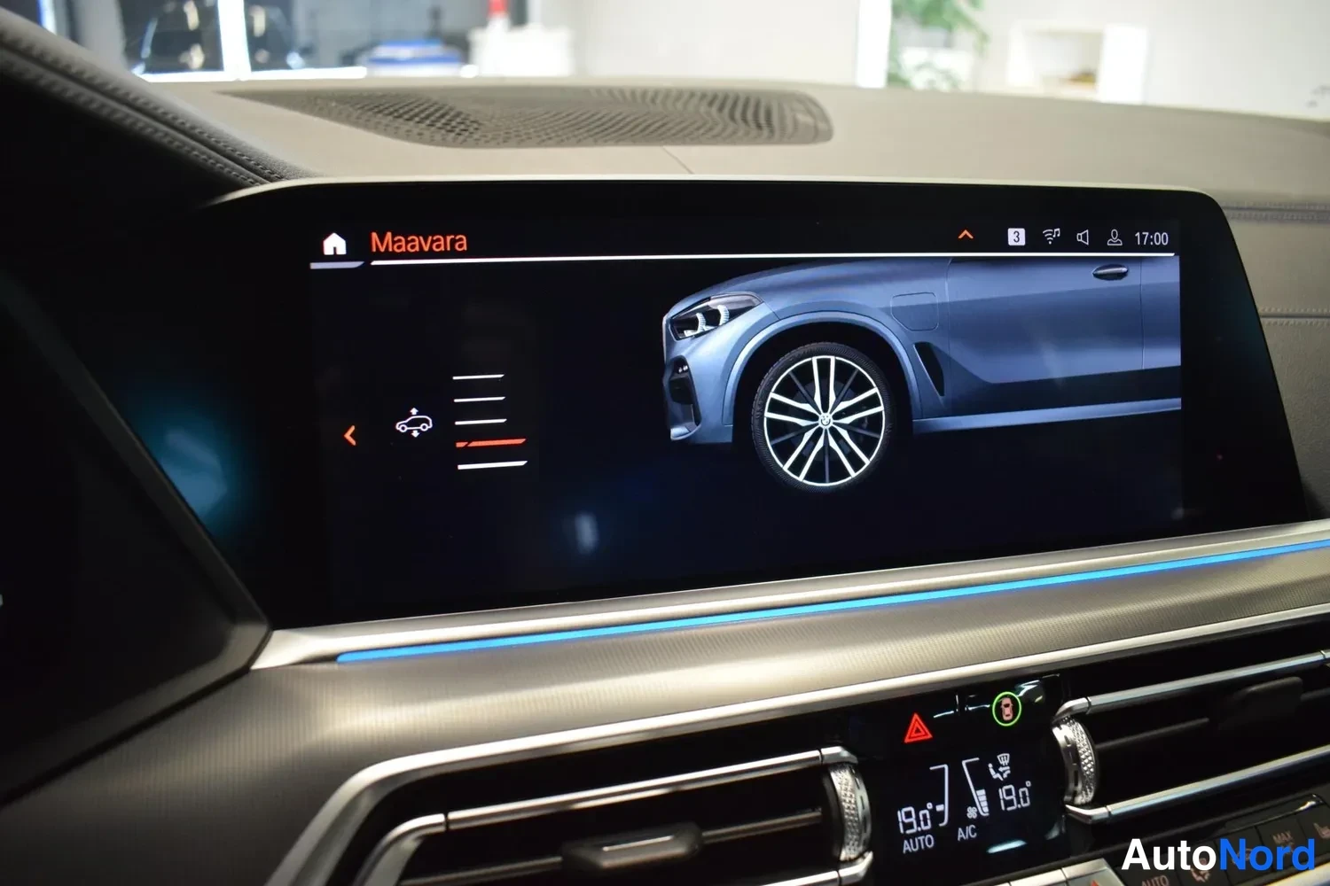 Muu: Auton infotainment-näytön Maavara-valikko, jossa on ajoneuvon kuva ja asetusluettelo; infonäytön alla näkyvät ilmastointilaitteen napit, lämpötilat 19,0 asti mo