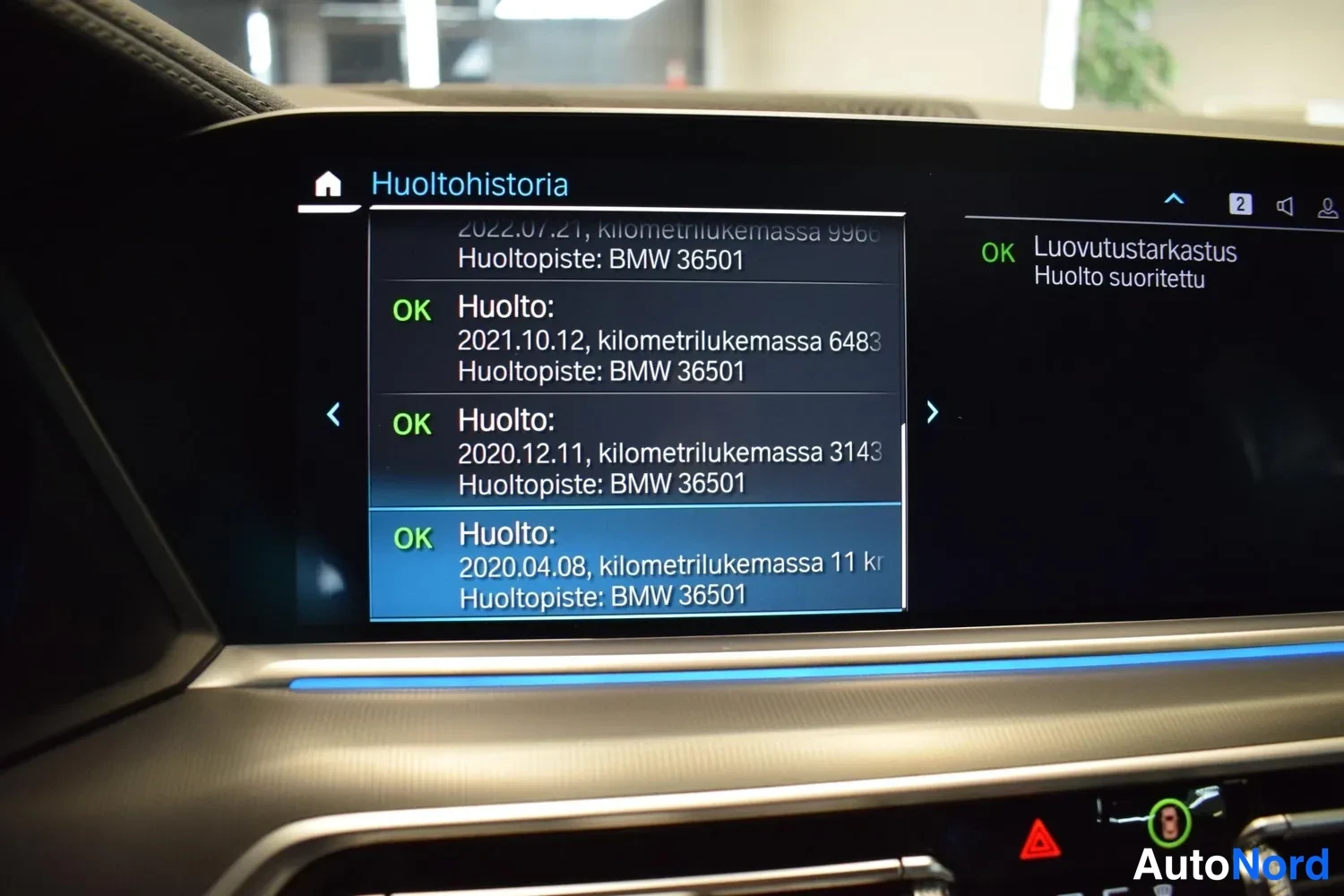 Muu: Infotainment-näytön Huoltohistoria-sivu, jossa luettelossa huoltoja vuosilta 2020–2022, huoltopisteenä BMW 36501, sekä Luovutustarkastus tehty.