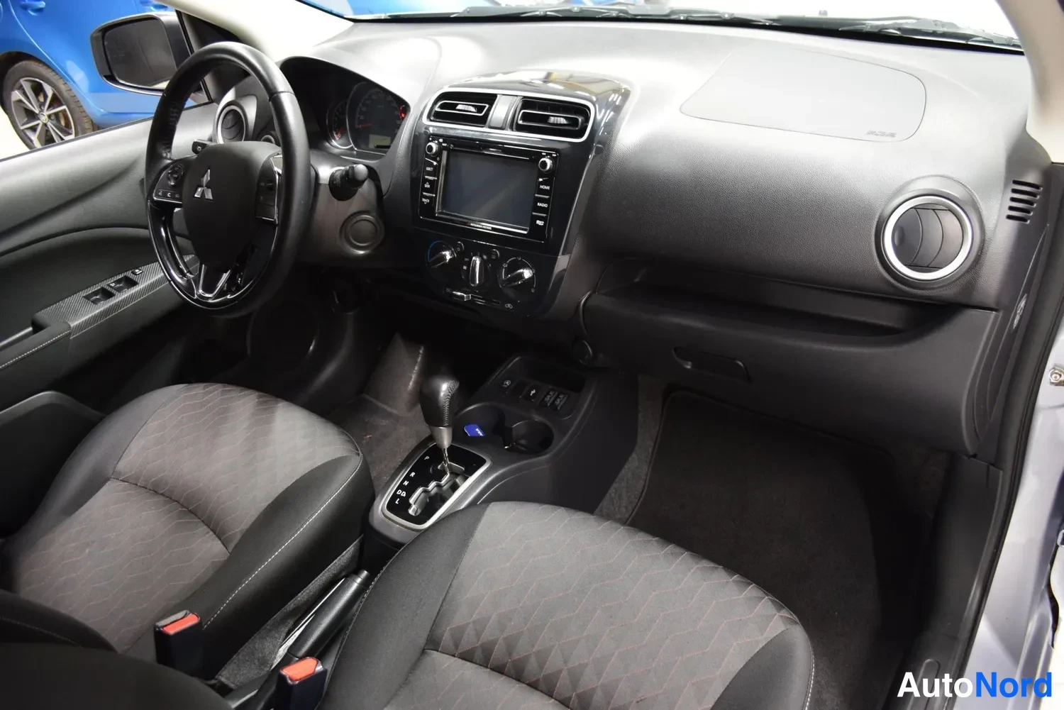 Muu: Kojelauta ja ohjaamo Mitsubishi-merkillä ohjauspyörässä: näytöllinen radioyksikkö, automaattivaihteen valitsin ja etupenkit.