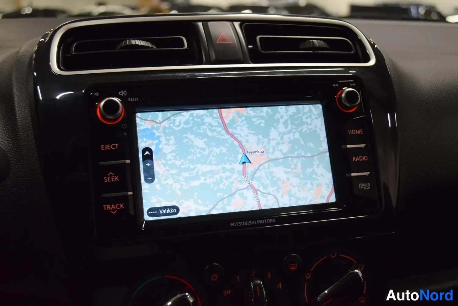 Muu: Mitsubishi Motors -multimediajärjestelmän näyttö näyttää karttanavigaatiota Hyvinkään alueella, vasemmalla EJECT-, SEEK- ja TRACK-napit, oikealla HOME- ja RADIO