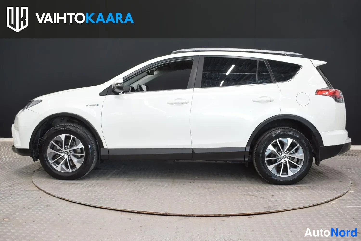 Sivulta: Valkoinen Toyota RAV4 -maastoauto sivuprofiililtaan studiokuvassa mustaa taustaa vasten.