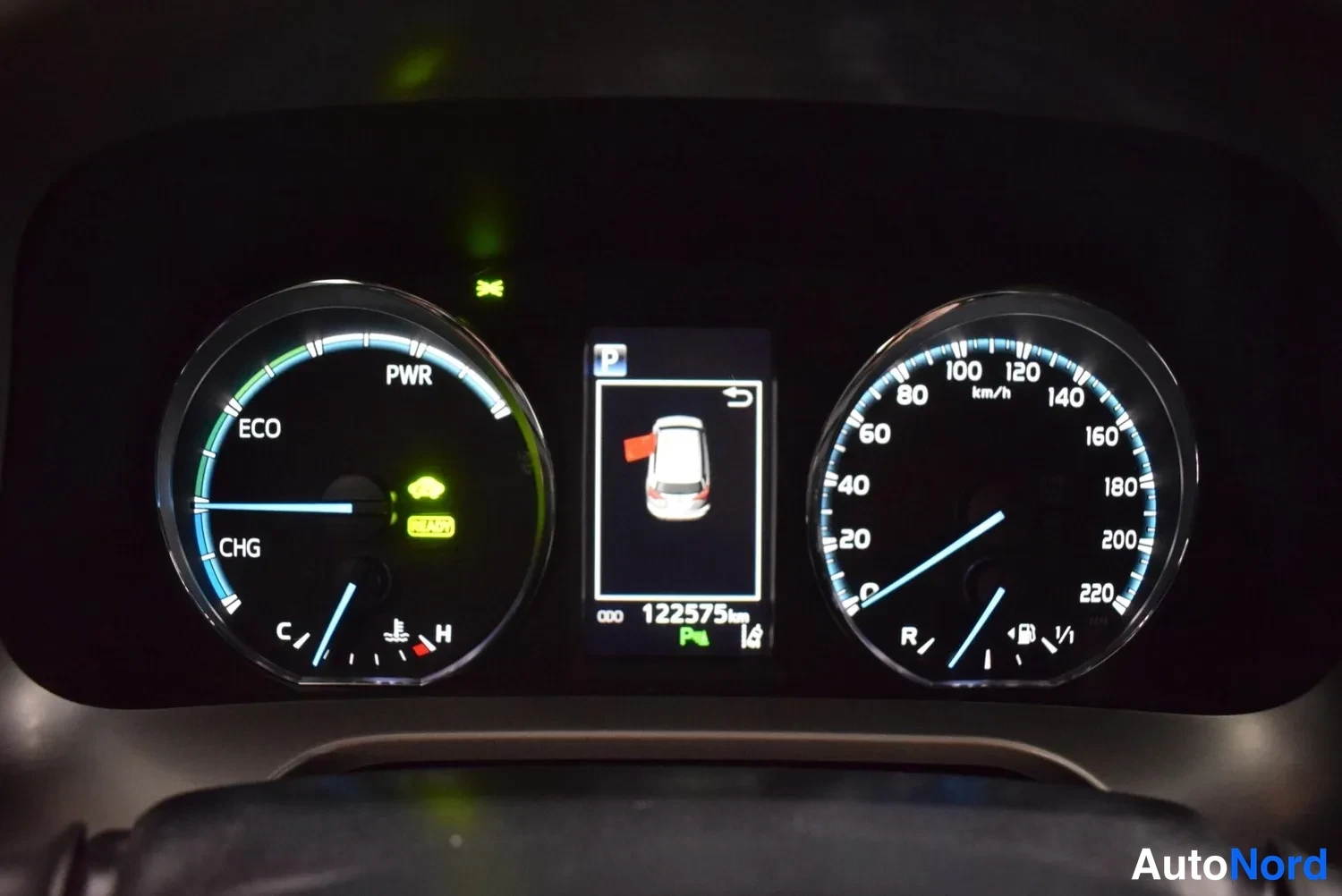 Muu: Hybridiauton mittaristö: voimamittari PWR/ECO/CHG-alueella, nopeusmittari 0–220 km/h ja keskinäytössä pysäköinti-ikonilla lukema 122575 km.