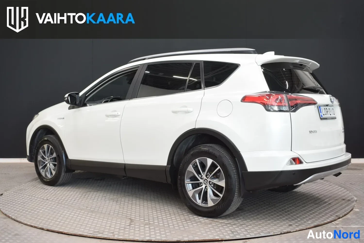 Takaviisto: Valkoinen Toyota RAV4 takakulmasta vasemmalle kääntyneenä studiokuvassa.