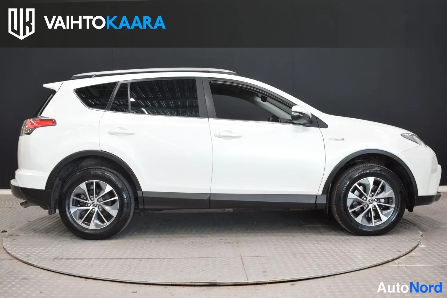 Sivulta: Valkoisen Toyota RAV4:n sivukuva oikealta, koko auto kuvattuna studion mustaa taustaa vasten.