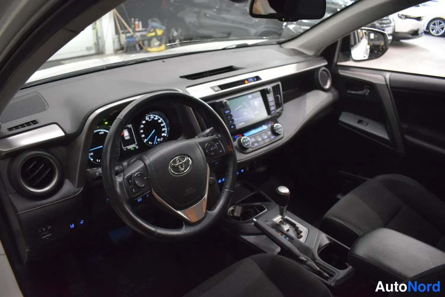 Muu: Toyota RAV4:n ohjaamo vasemmalta: ratti Toyota-merkillä, mittaristo, kosketusnäyttö ja vaihdekeila.
