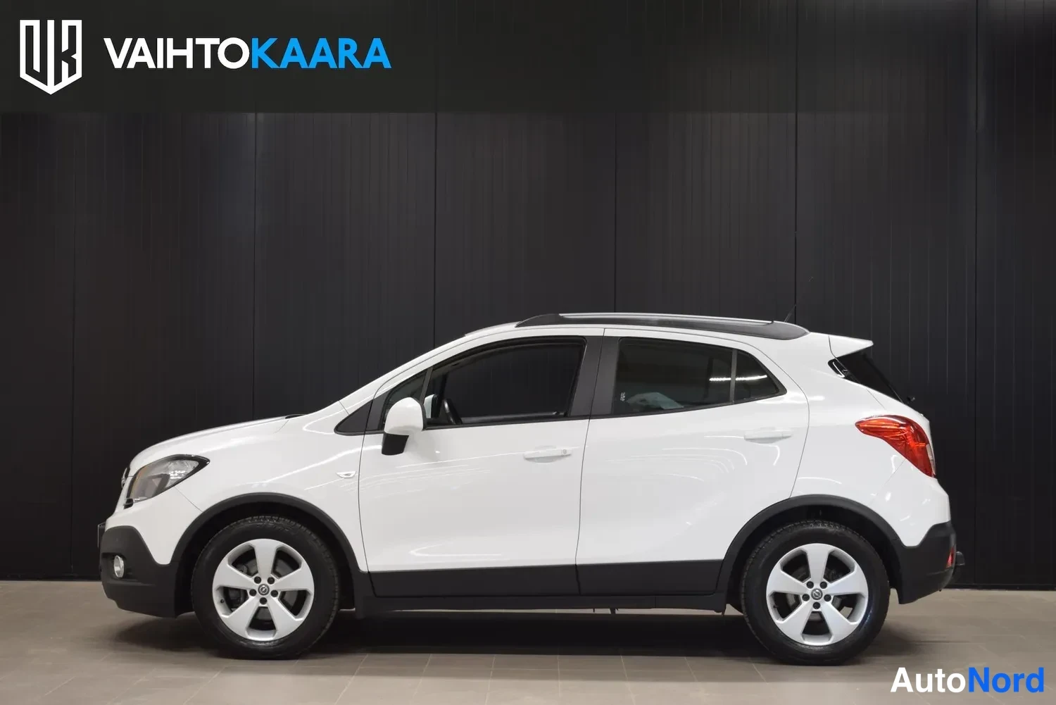 Etuviisto, nokka vasemmalle: Valkoinen Opel Mokka sivulta, etuosa hieman kuvassa; keulavalo ja kylki näkyvissä.