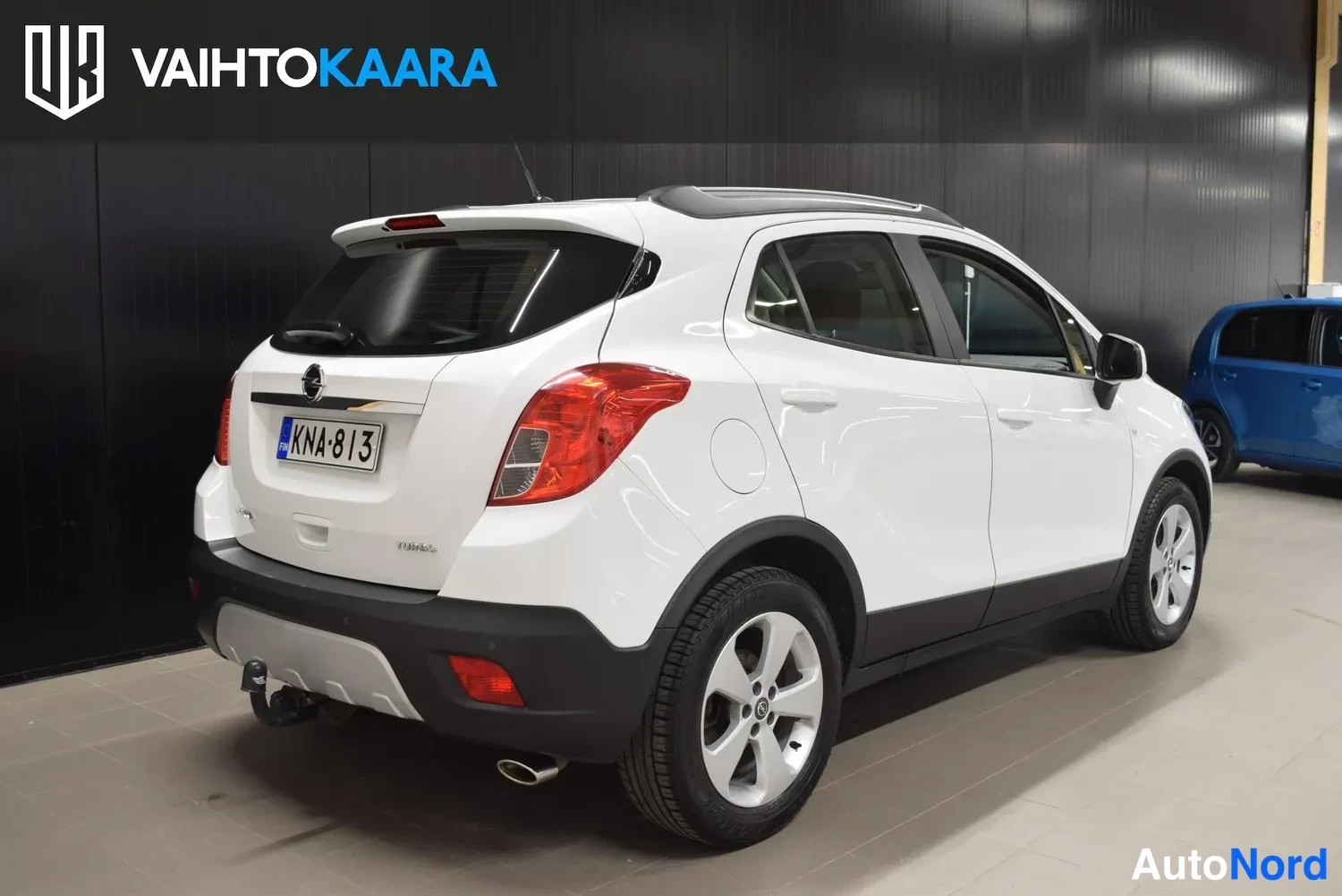 Takaviisto: Valkoinen Opel Mokka takakulmasta, takavalo, rekisterikilpi ja kylki näkyvissä.