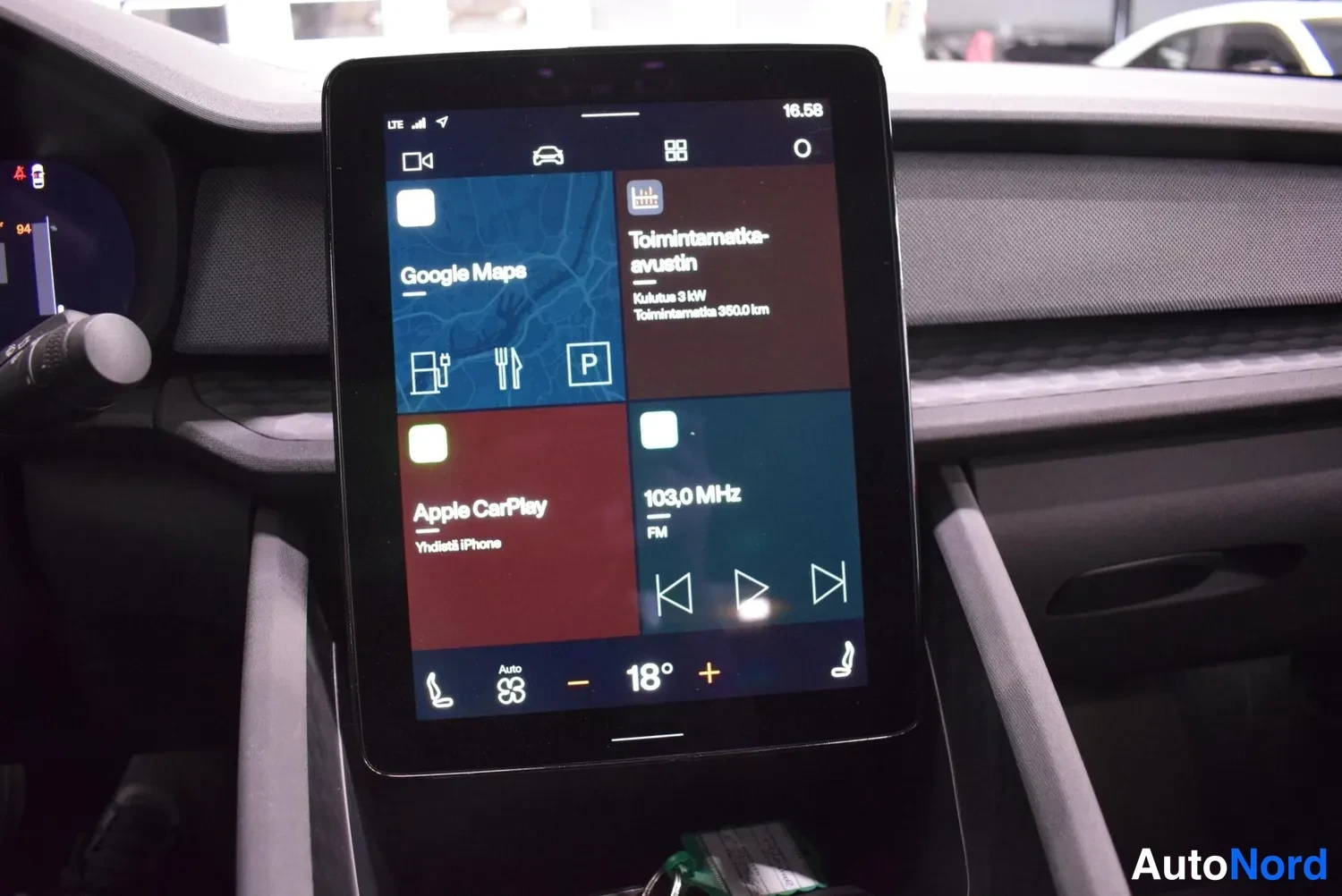 Muu: Yhtenäinen pystykeskinäyttö lähikuvassa: Google Maps, Apple CarPlay, radiotaajuus 103,0 MHz ja lämpötila 18 astetta.