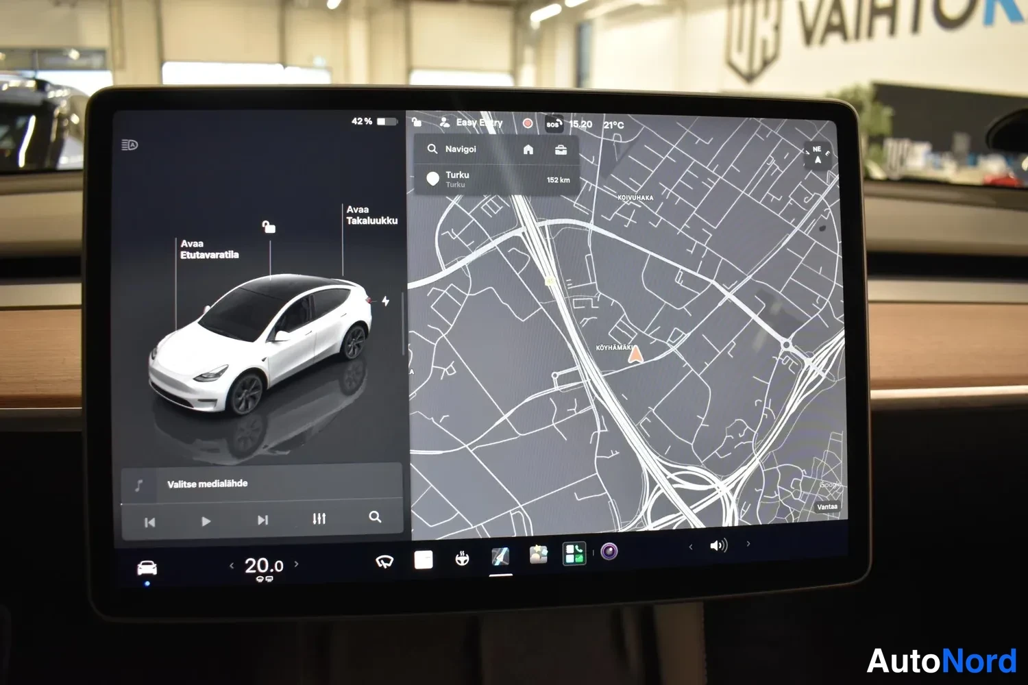 Yksityiskohta: Tesla-automobilella näkyy kosketusnäytön karttanäkymä, jossa on teksti 'Avaa Etuvaratila' ja 'Avaa Takaikkunoita'.