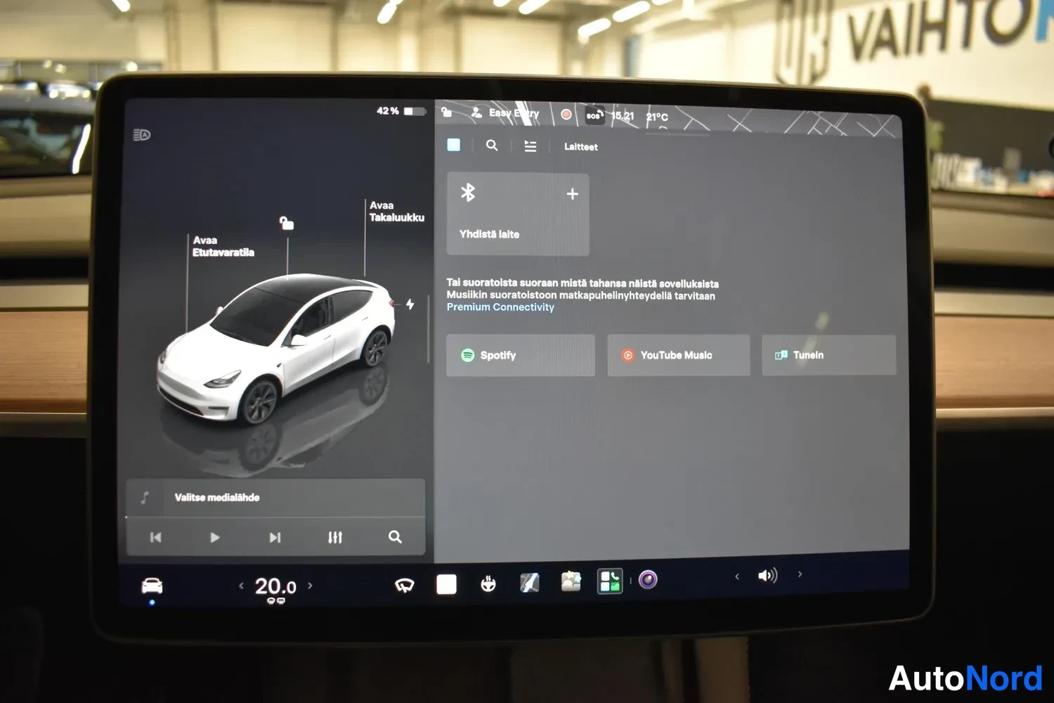 Yksityiskohta: Tesla-automobilella näkyy kosketusnäytön valikko, jossa on teksti 'Avaa Etuvaratila' ja 'Avaa Takaikkunoita'.